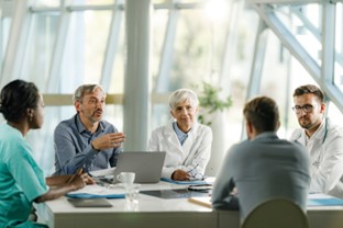 A group of doctors and business people sit at a conference table, having a discussion. | Medi-Weightloss®