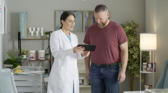 A doctor and her patient review his weight loss results on a tablet together. | Medi-Weightloss